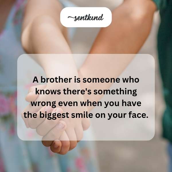 Two brothers are embracing, one with a forced smile and the other with a concerned expression.