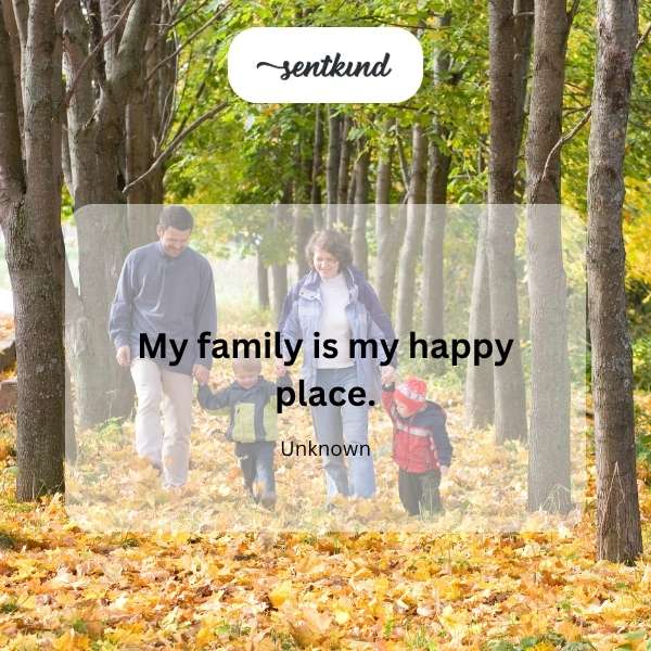 A smiling family is gathered closely together in a sunlit park.