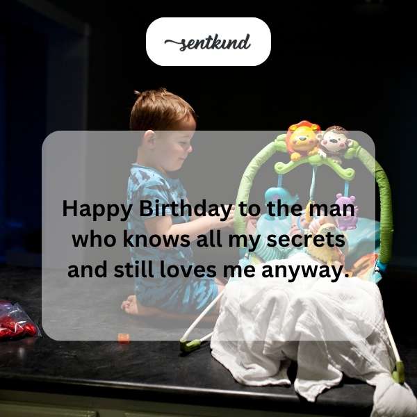 A smiling man is holding a birthday cake with lit candles.