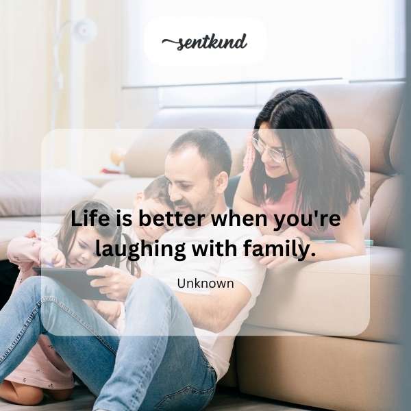 A family laughing together outdoors in a sunlit park.