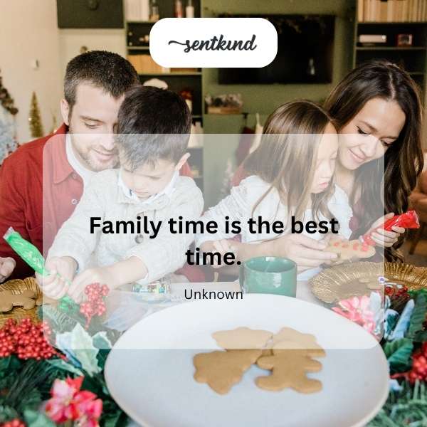 A group of smiling people are gathered together indoors, possibly around a table or fireplace.