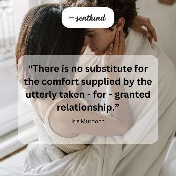A couple sits closely together on a worn couch, relaxed and at ease.