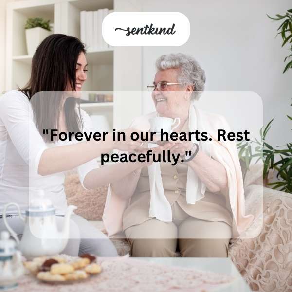 A framed vintage photograph of a warm, smiling elderly woman rests on a wooden surface next to a small bouquet of forget-me-not flowers.