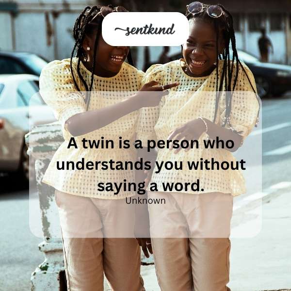 Two identical twins are smiling and embracing each other.