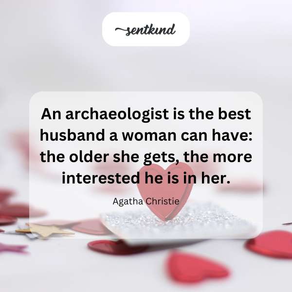 An elderly woman smiles while an archaeologist examines ancient artifacts nearby.