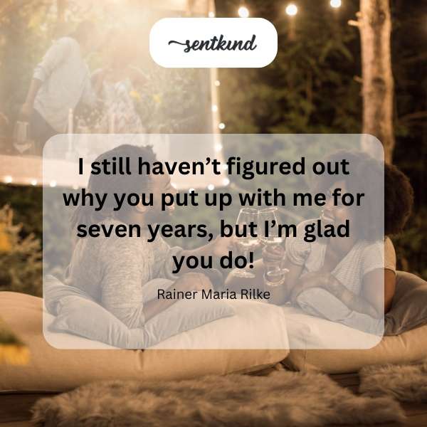 A couple sits closely together on a park bench, smiling and looking at each other.