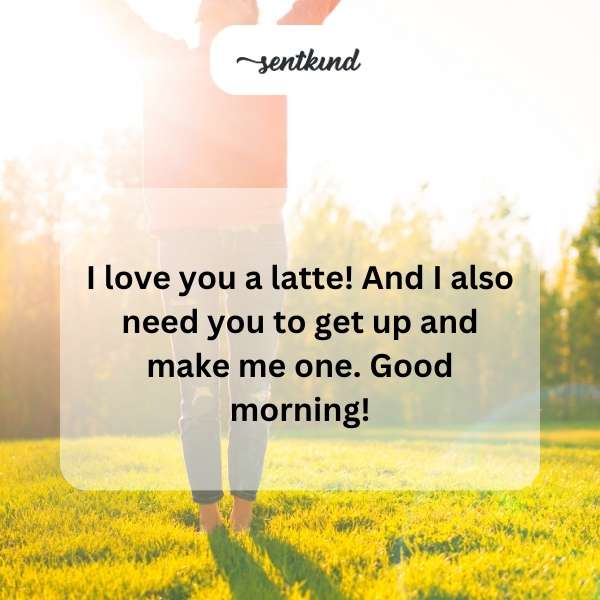 A steaming latte with a heart design sits on a bedside table next to a person's hand reaching for it.