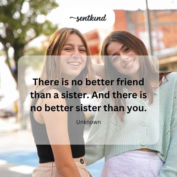 Two smiling sisters are hugging each other affectionately outdoors on a sunny day.