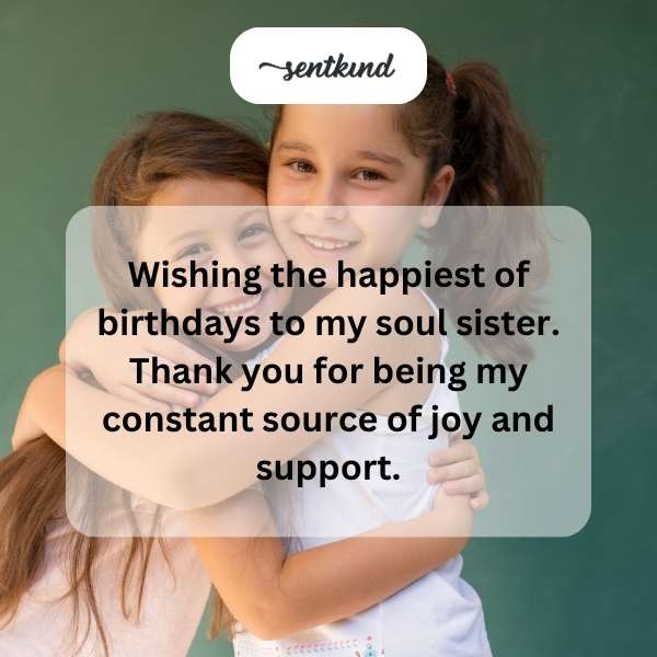 Two smiling women hugging each other warmly during a birthday celebration.