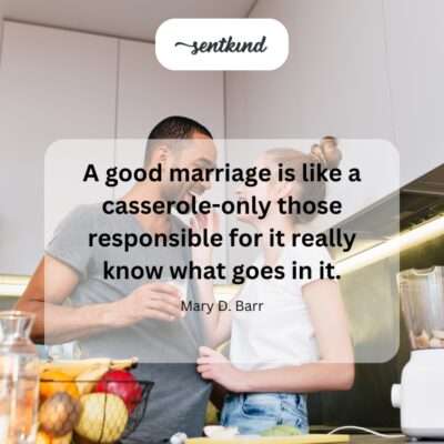 A warm casserole dish sits on a wooden table with a smiling couple blurred in the background in a cozy kitchen.