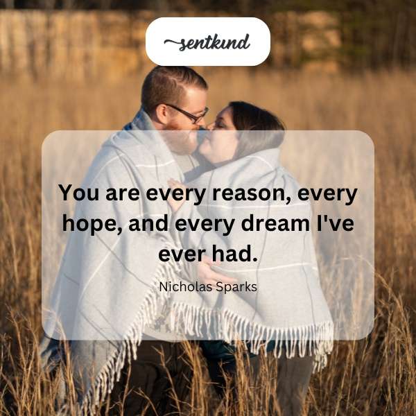 A couple embraces tenderly against a sunset backdrop.