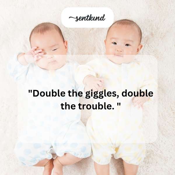 Two identical babies are sitting side-by-side, smiling mischievously.