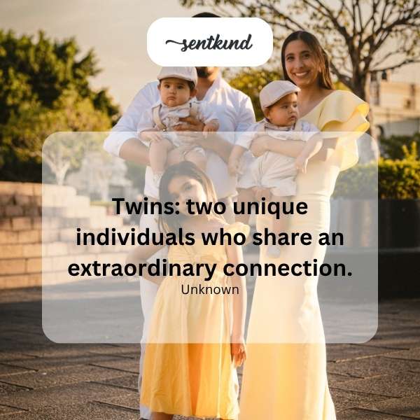 Identical twins standing side-by-side, smiling warmly.