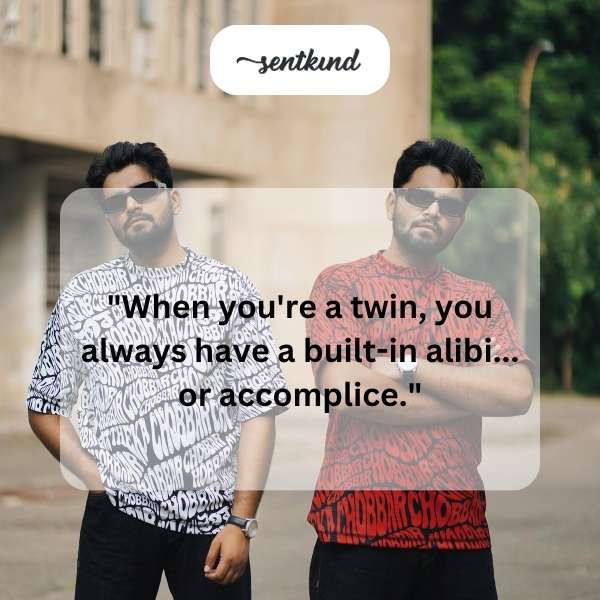 Two identical twins stand side-by-side smiling mischievously.
