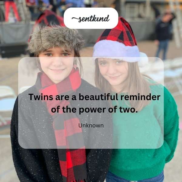 Identical twins standing side-by-side, smiling brightly at the camera.