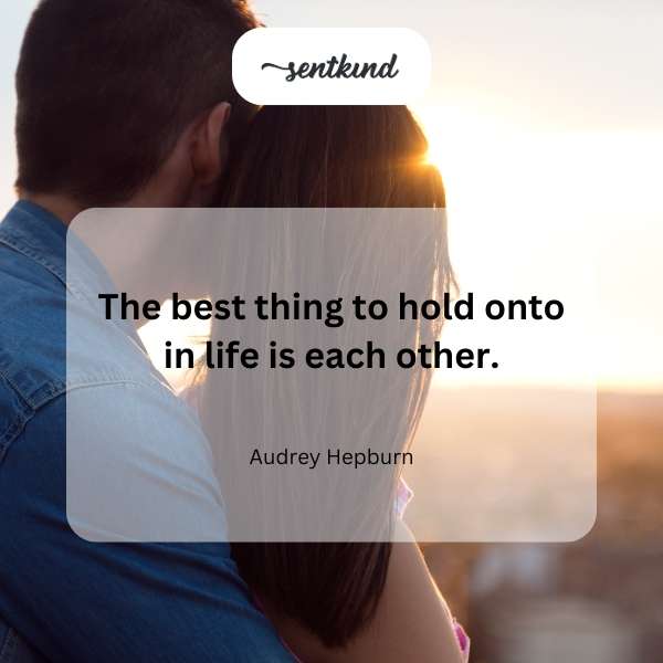 A couple embraces warmly, silhouetted against a softly lit background.