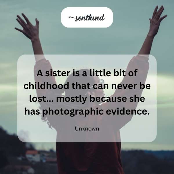 Two sisters laugh together while looking through an old photo album filled with childhood pictures.