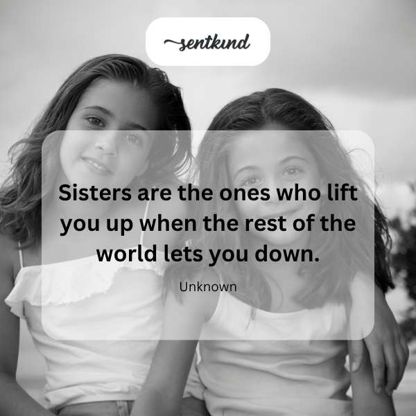 Two sisters are holding hands and smiling warmly at each other in a field.