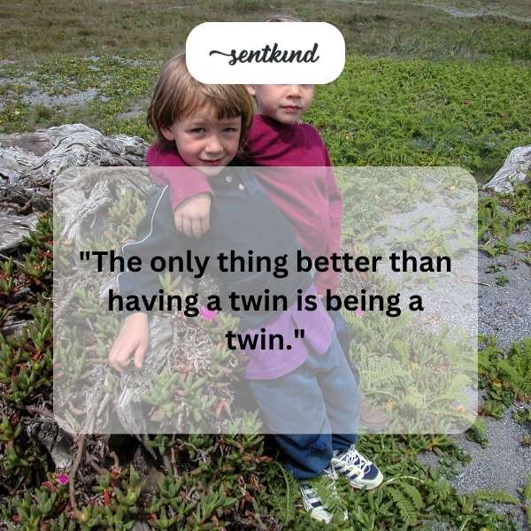 Two identical young girls are standing side-by-side, smiling brightly at the camera.