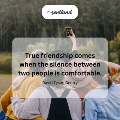 Two friends sit together comfortably on a park bench, looking out at a view in peaceful silence.