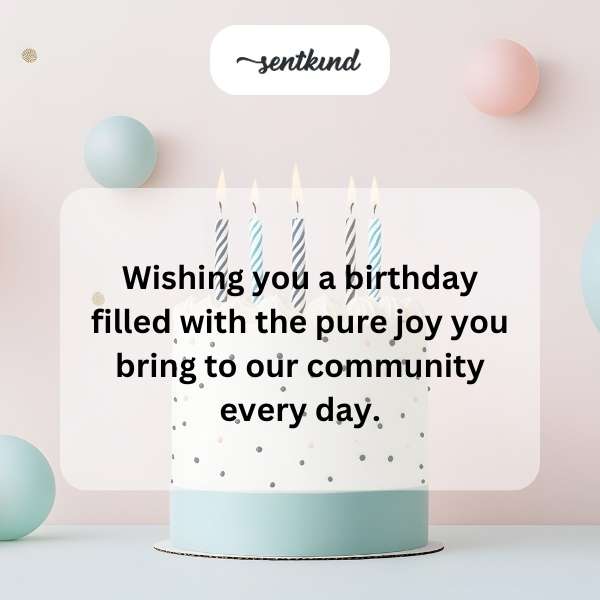 A warmly lit gathering with people smiling and celebrating around a decorated cake.